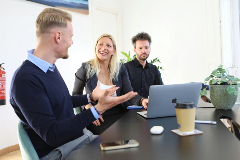 three people sit around a table and talk