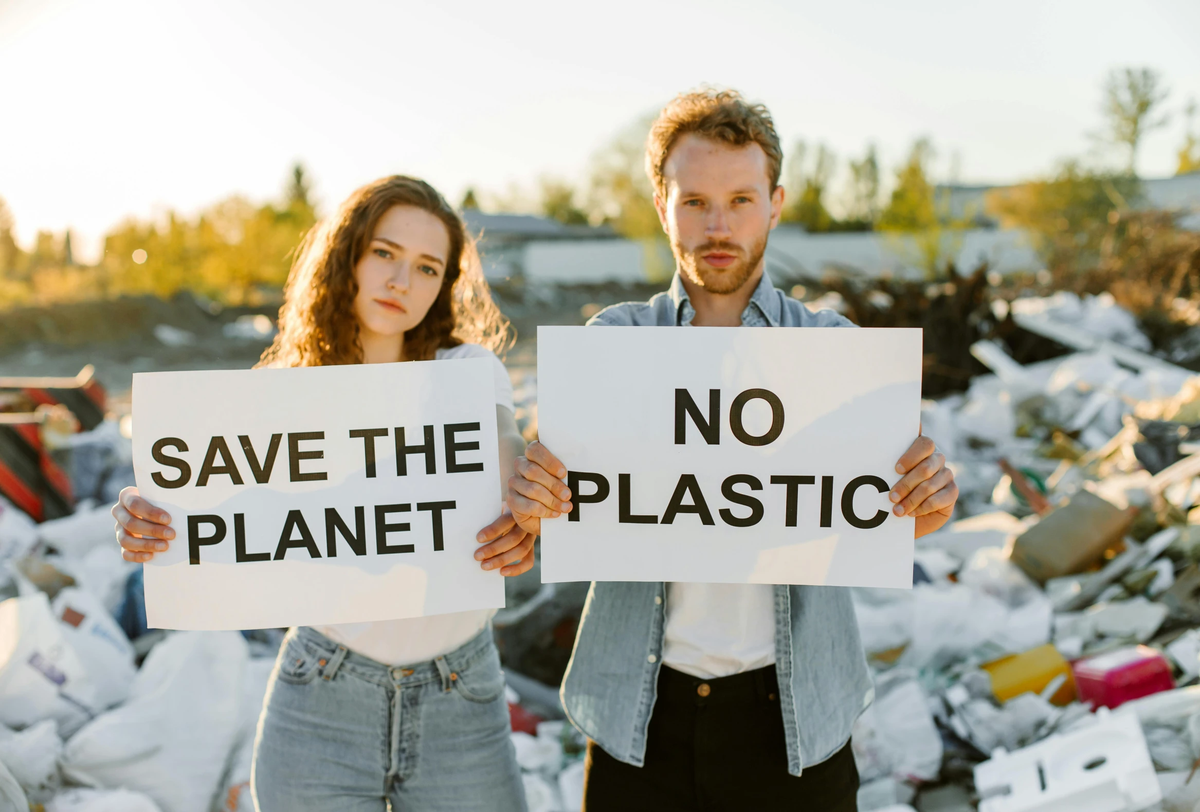 two people holding signs on a pile of trash