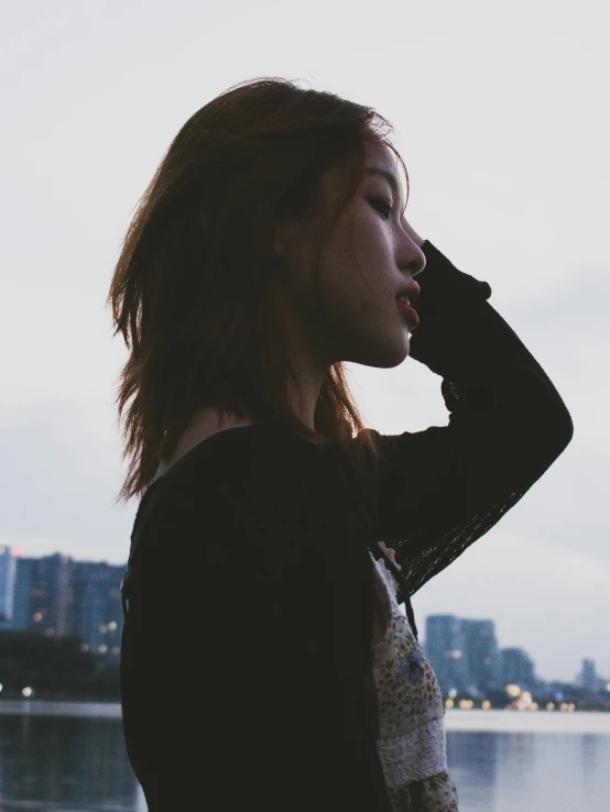 a woman standing with her hand to her ear and looking into the distance