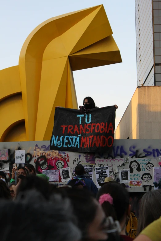 a man holding a sign and standing next to a large yellow building