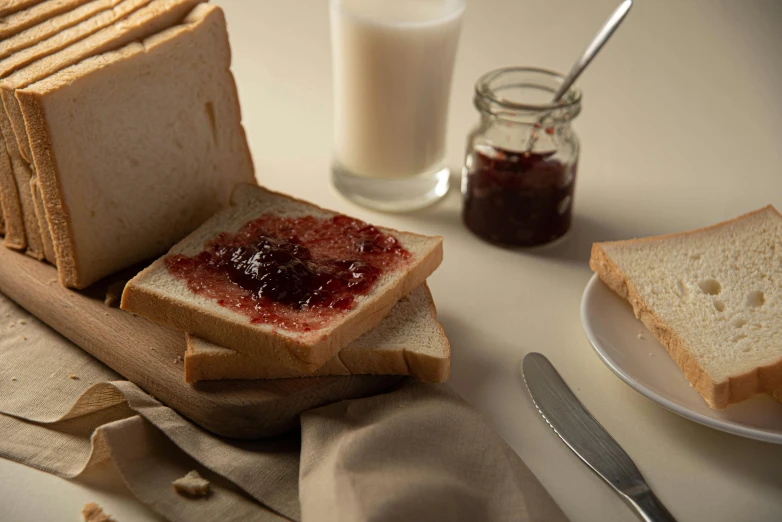 toasted bread, jam and spoon sit on a white table