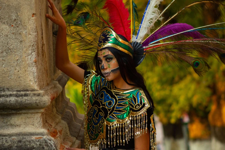 a girl in a feather costume poses in front of a pillar