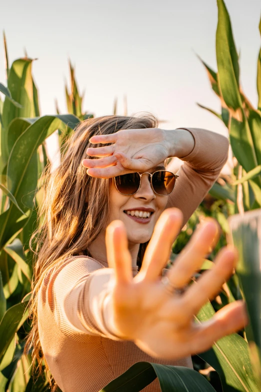 a woman in sunglasses standing next to a corn field