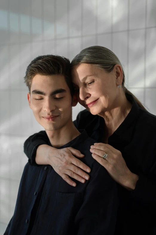 an older woman with a younger man who is hugging her