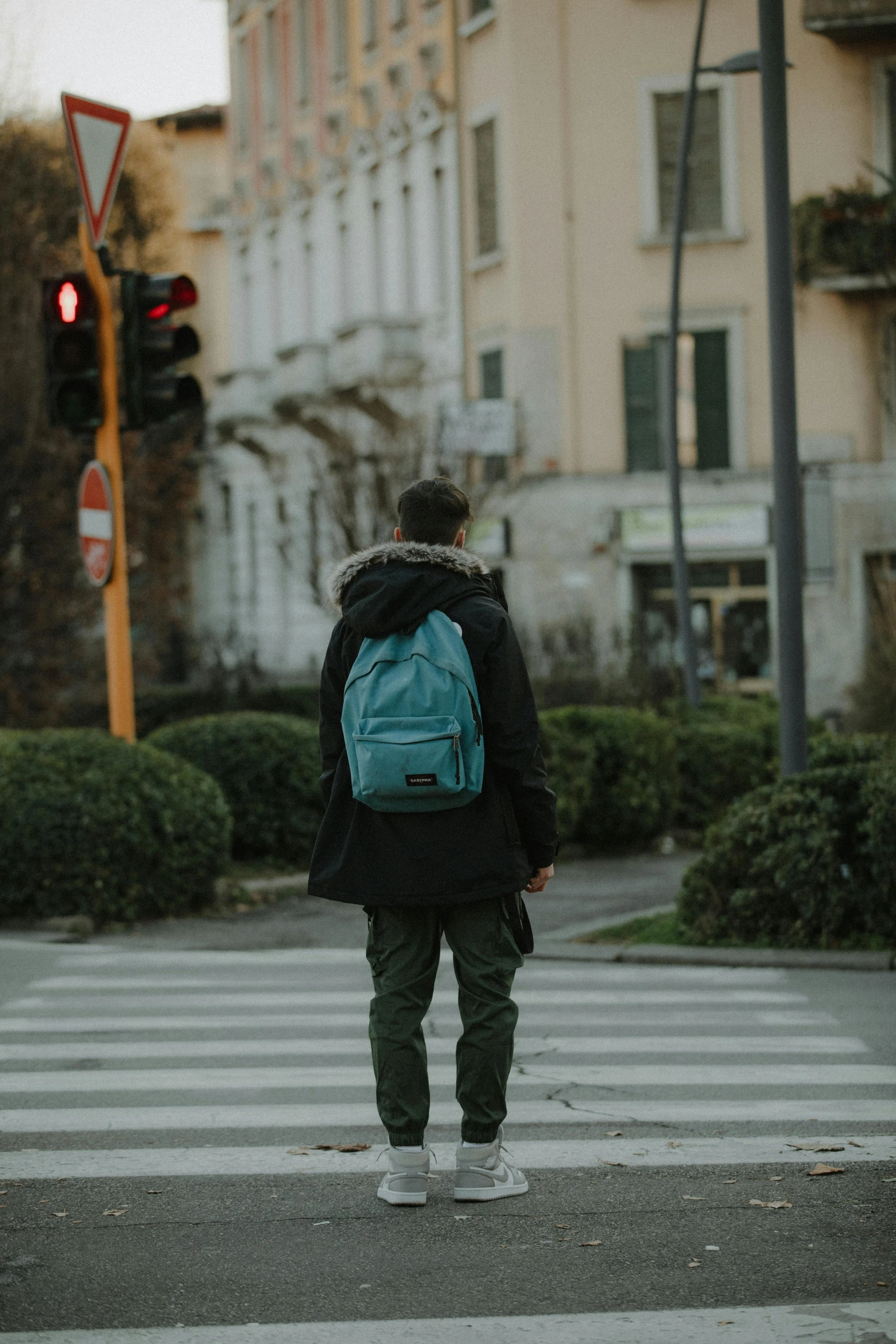 a person wearing a backpack in the street at a stop light