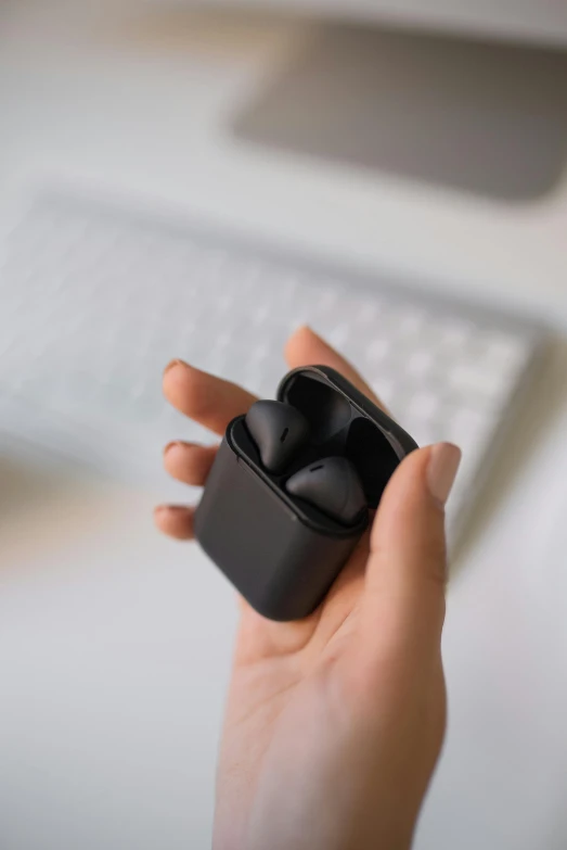 a woman's hand holding an air buds in her right hand