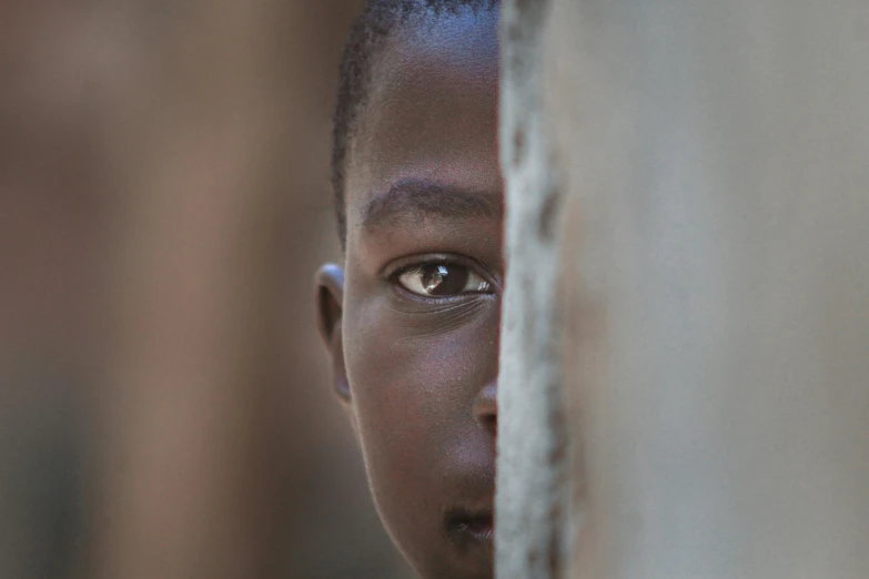 a boy peeking over a door and staring into the distance