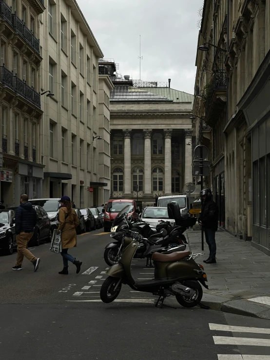 a scooter and some cars and people on the street