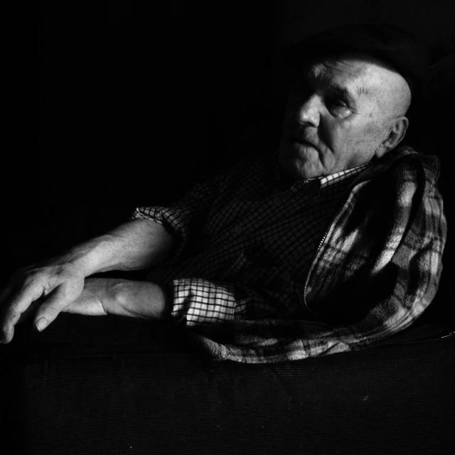a black and white po of an old man wrapped up with a blanket