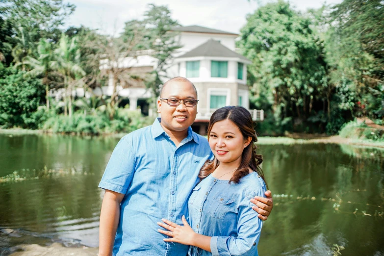 man and woman pose in front of a house by water