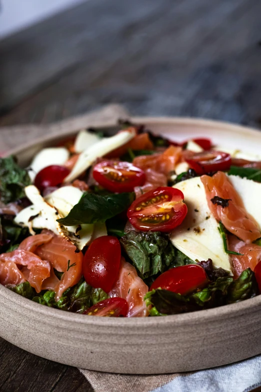 a salad with spinach, tomato slices and parmesan cheese