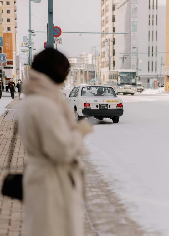 a woman walks down the street while a taxi passes by