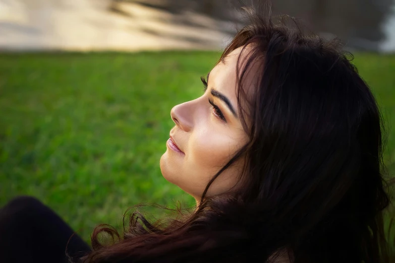 young woman laying down in the grass looking away from the camera