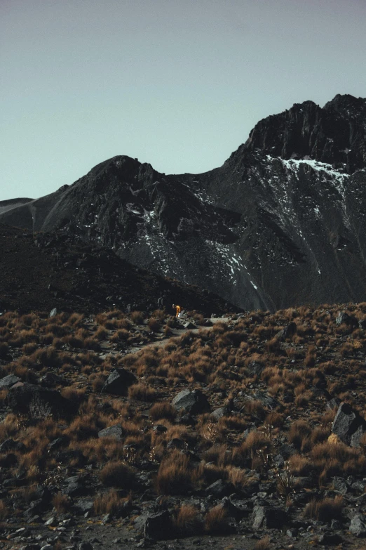 the landscape of this remote area consists of rocky mountains, brown grass and a small house