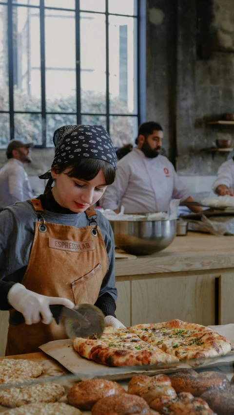 a woman is making pizza in a kitchen