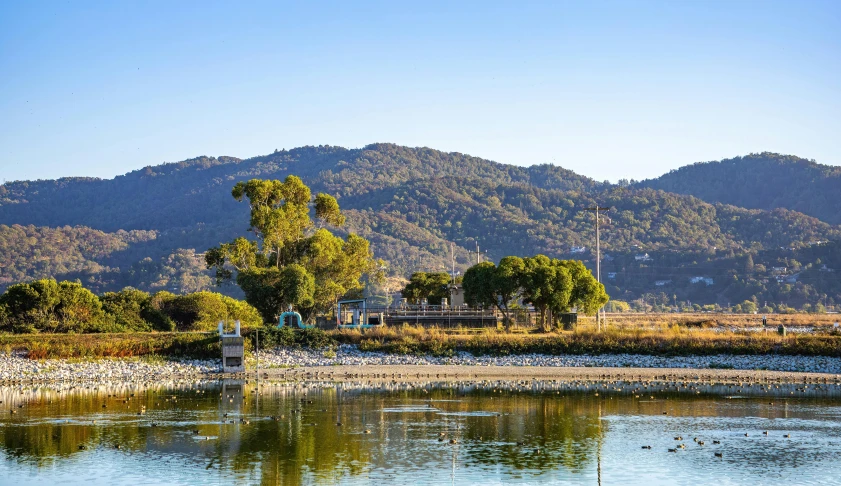 a mountain side view with a body of water in the foreground