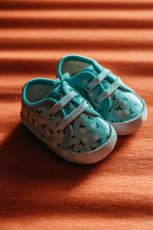 a pair of baby shoes sitting on top of a bed