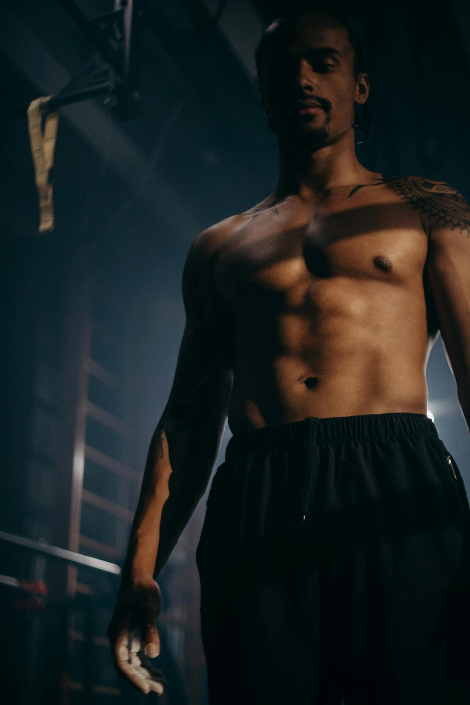 man in gym shorts looking to side in dimly lit room