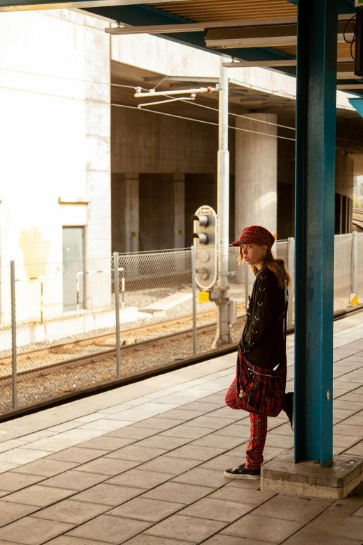 the young woman wearing a red hat is waiting for her train