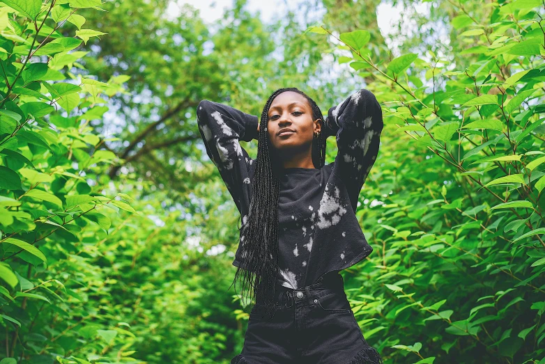 a black woman in a black dress standing among the trees