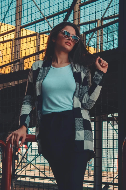 the young woman is posing near a metal fence