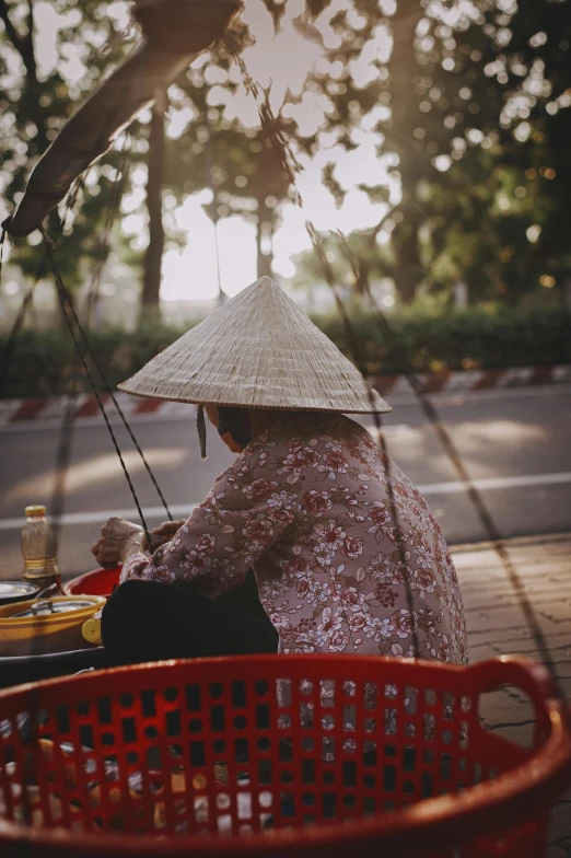 a woman with a hat and umbrella sitting on the sidewalk