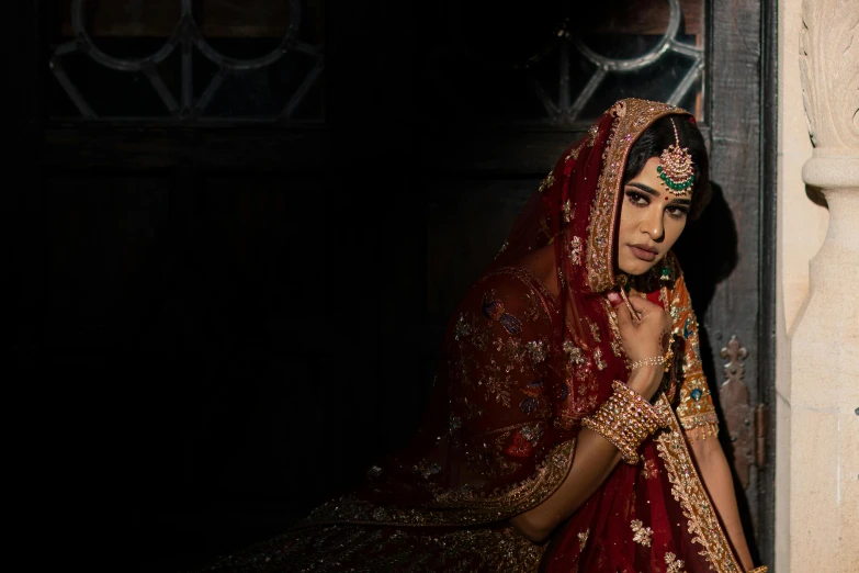 a woman in indian clothing sitting next to a doorway