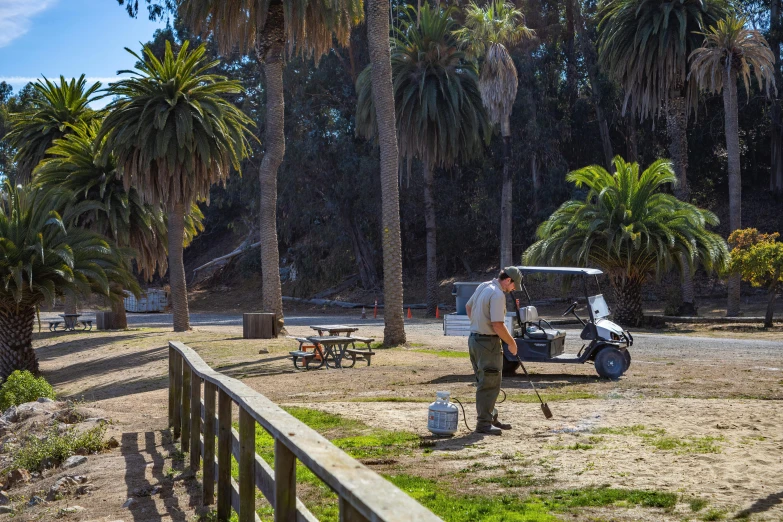 a man is tending to a parked golf cart