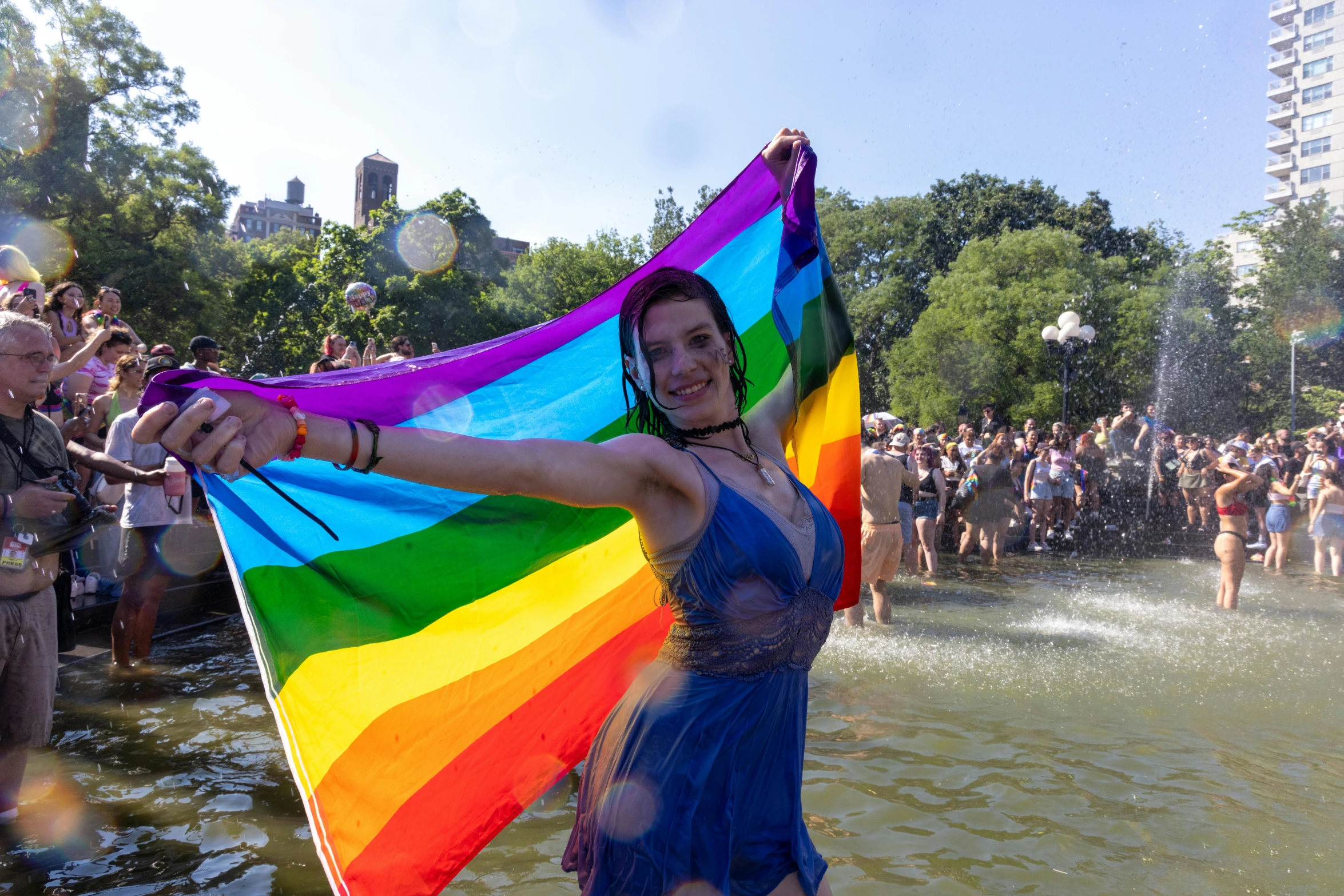 a woman is holding a rainbow flag in the water