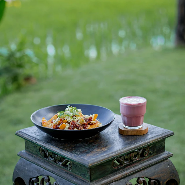 a bowl of food is next to a glass of milk on a small table