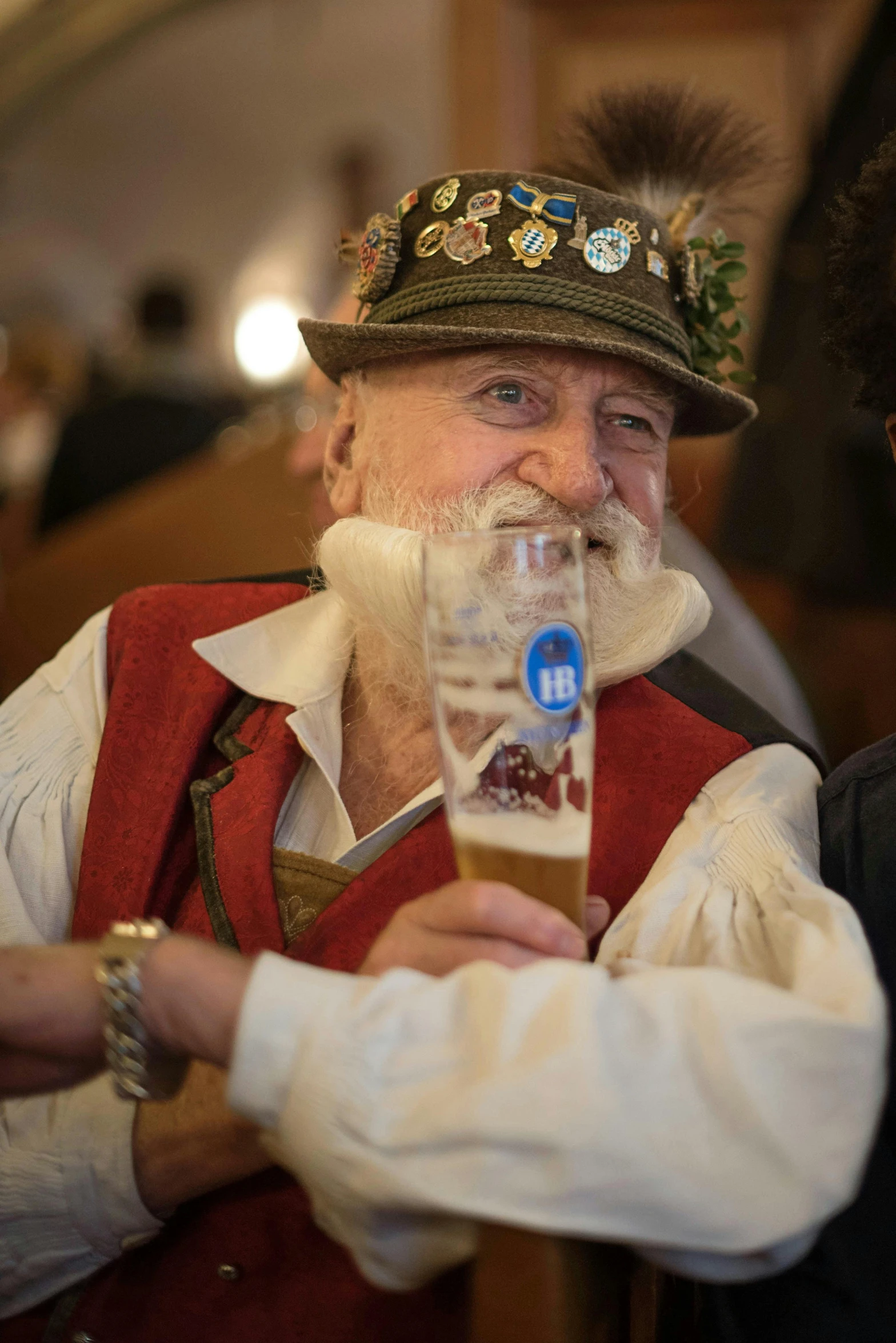 the older man in the hat is sipping his beer