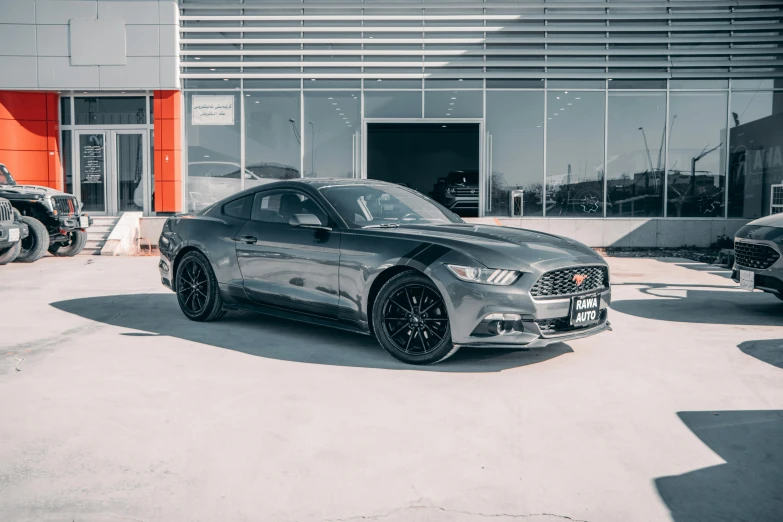 a silver mustang parked in front of a large orange building