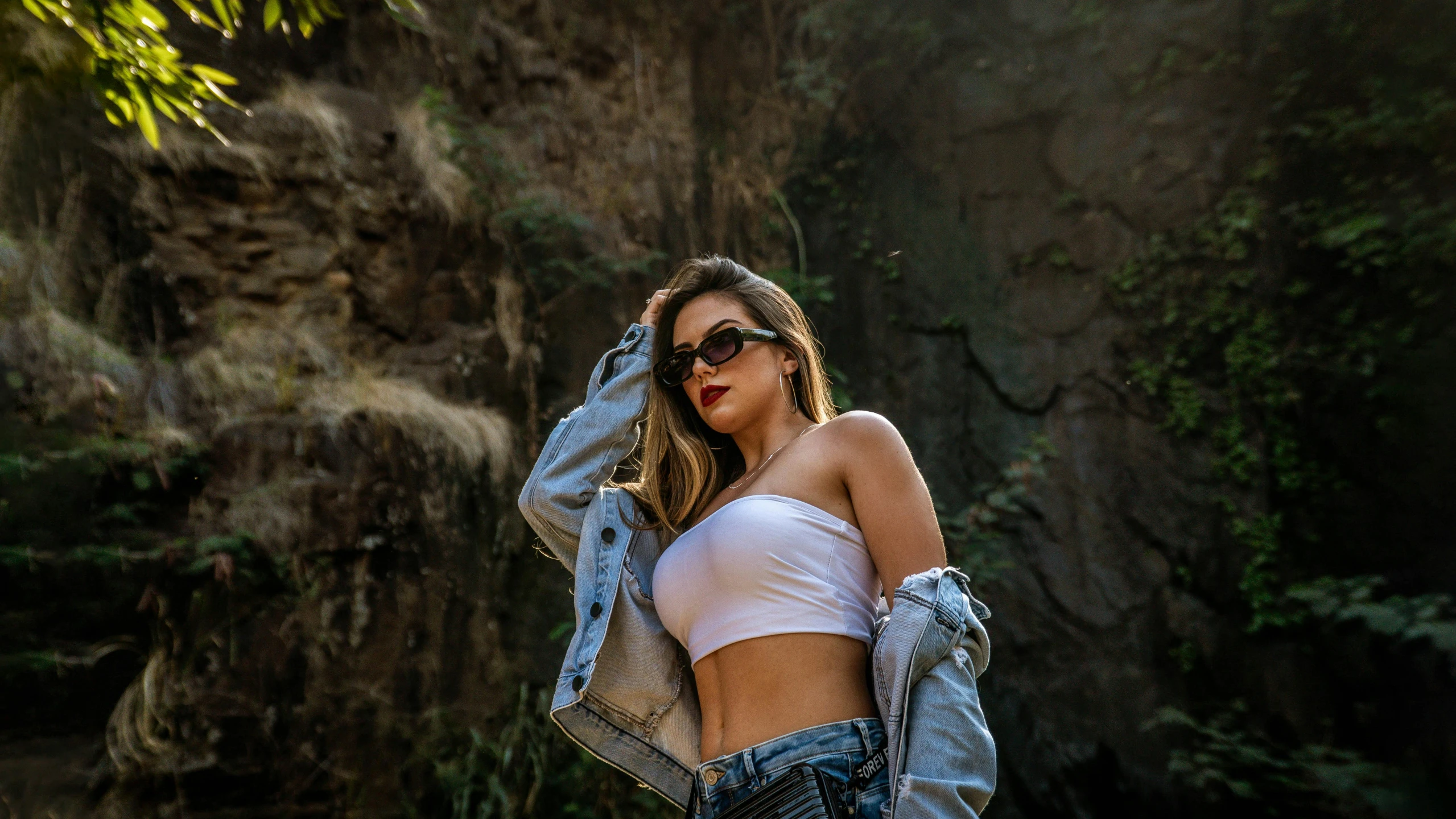 a young woman standing in the woods with a jean jacket