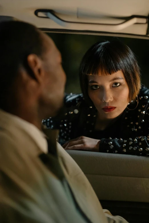 a woman sitting in the back seat of a car talking to a man