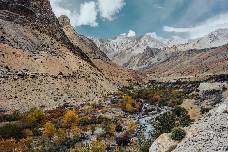 a stream running between some rocky mountains with sp vegetation