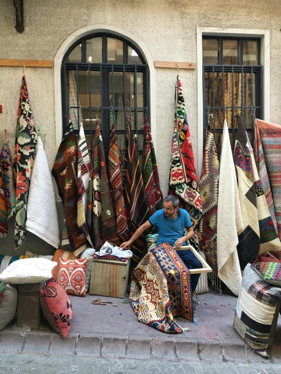 a woman sitting in a shop full of fabrics