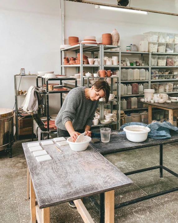 a woman in a pottery shop mixing a pot of water