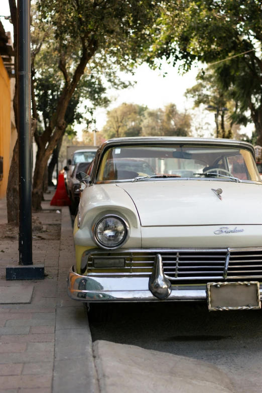 an old model car parked at a curb