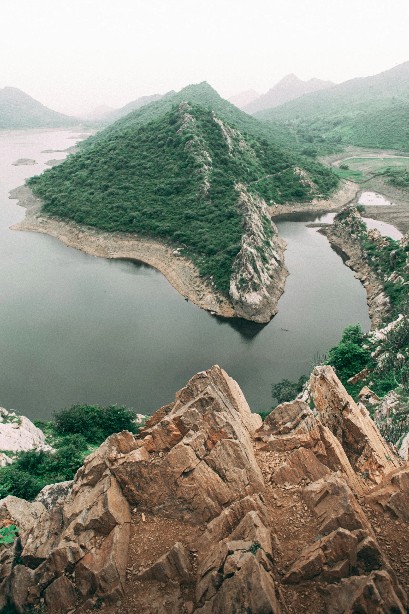 a green mountain and river surrounded by rocks