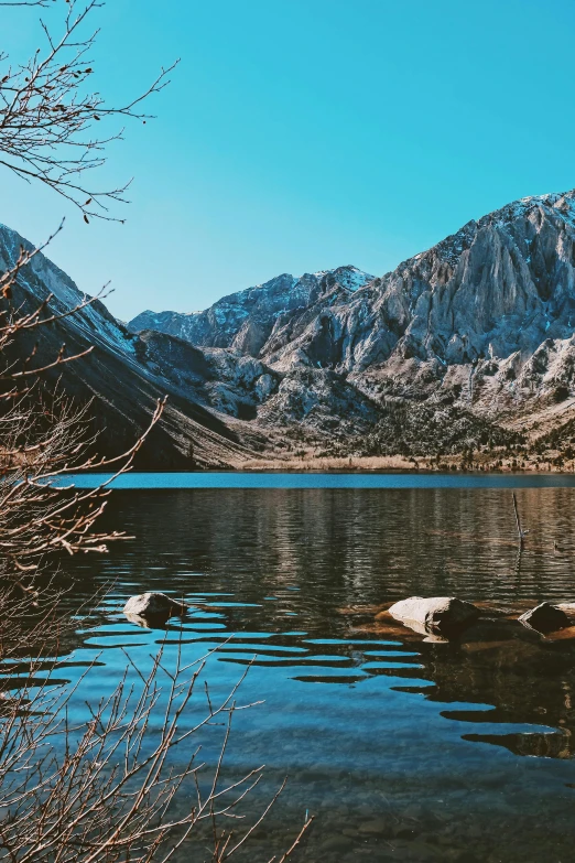 there is mountains in the distance, one with a rock on the bank and the other one with a large rock on the shore