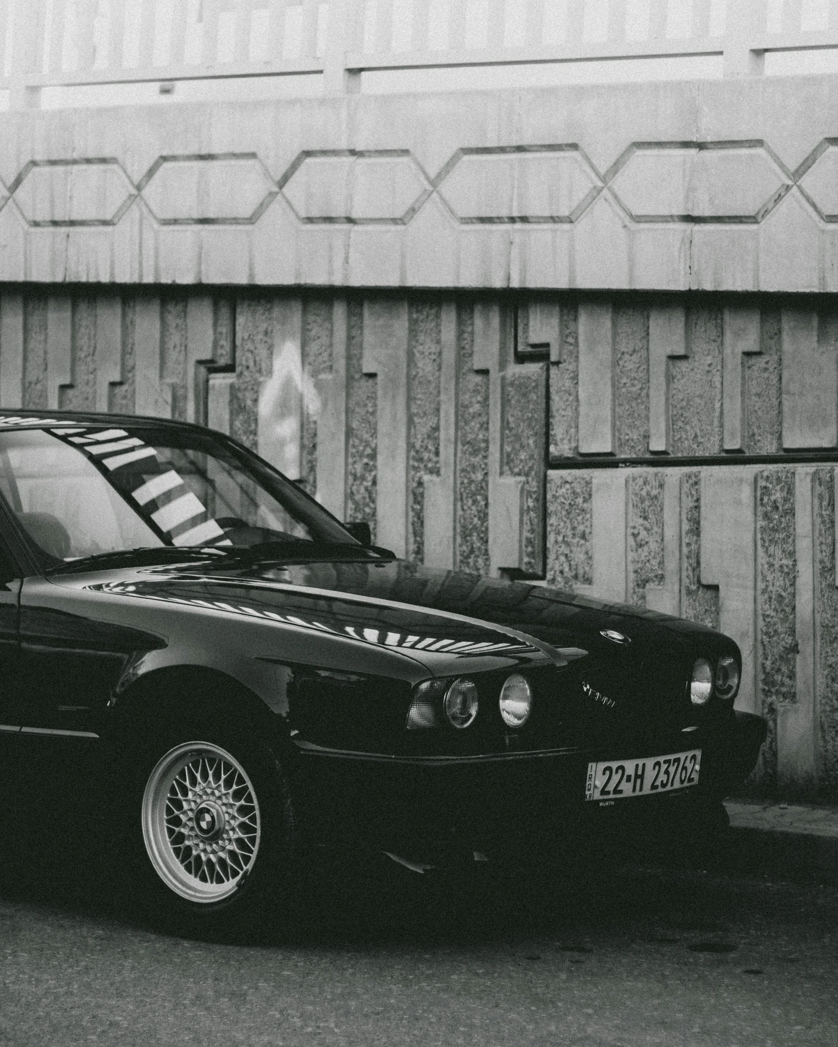 a black and white po of a black car parked by a wall