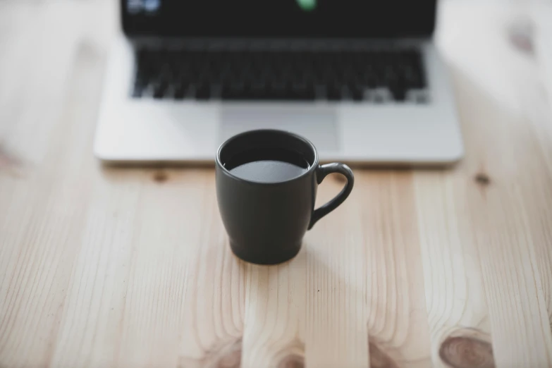 a coffee cup sitting next to an open laptop