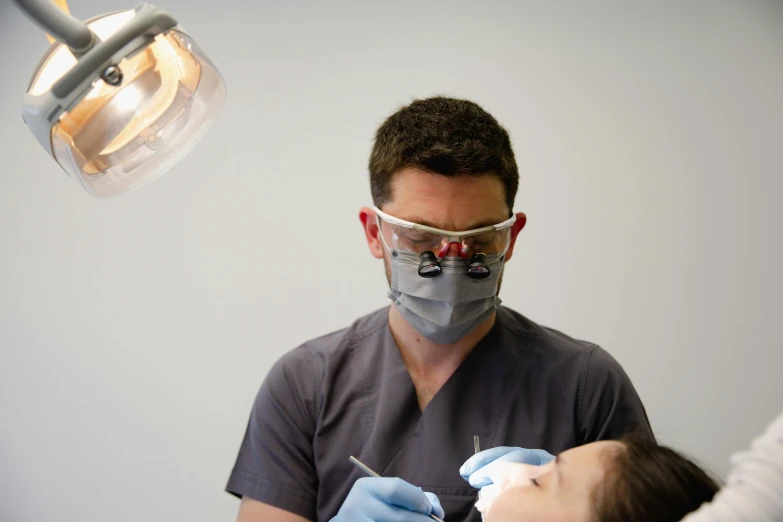 a man in a dentist mask and blue gloves