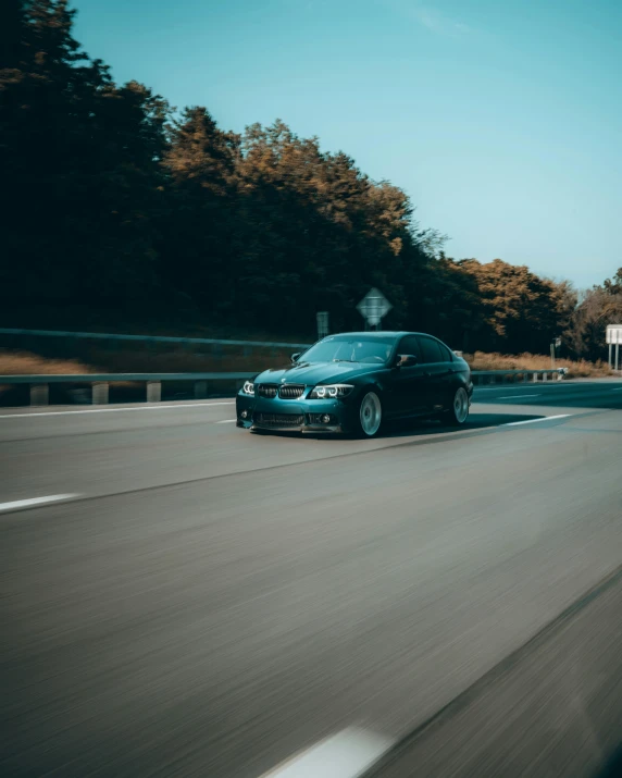 a black car driving down a road next to trees