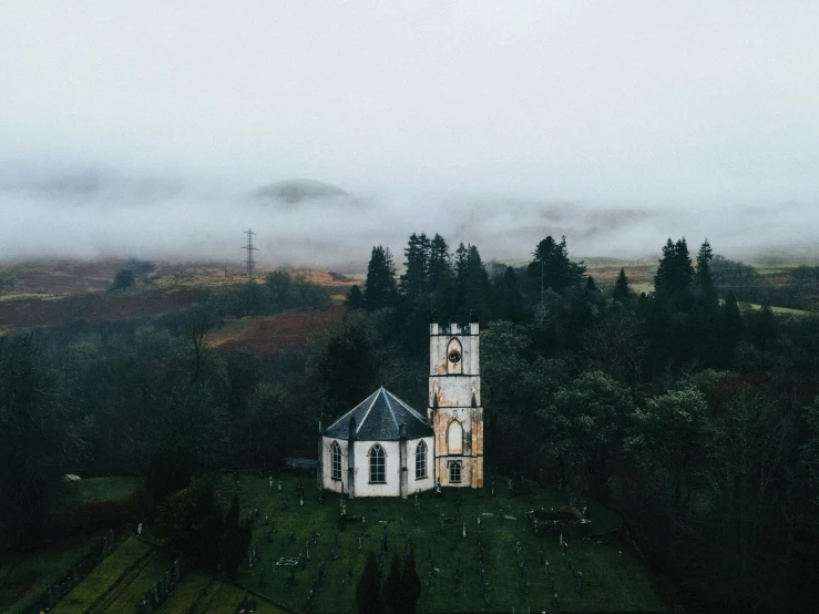 a white church on a hill with foggy skies
