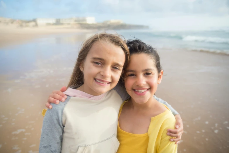 two girls on the beach taking a selfie with their arms around each other