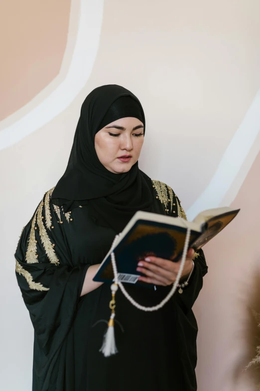 a woman wearing a hijab is holding a book