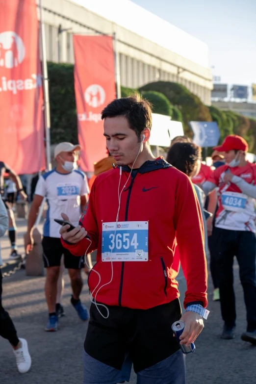 man in red shirt checking cell phone during race