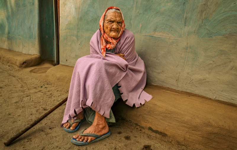 an elderly woman with an over sized head sitting next to a wall