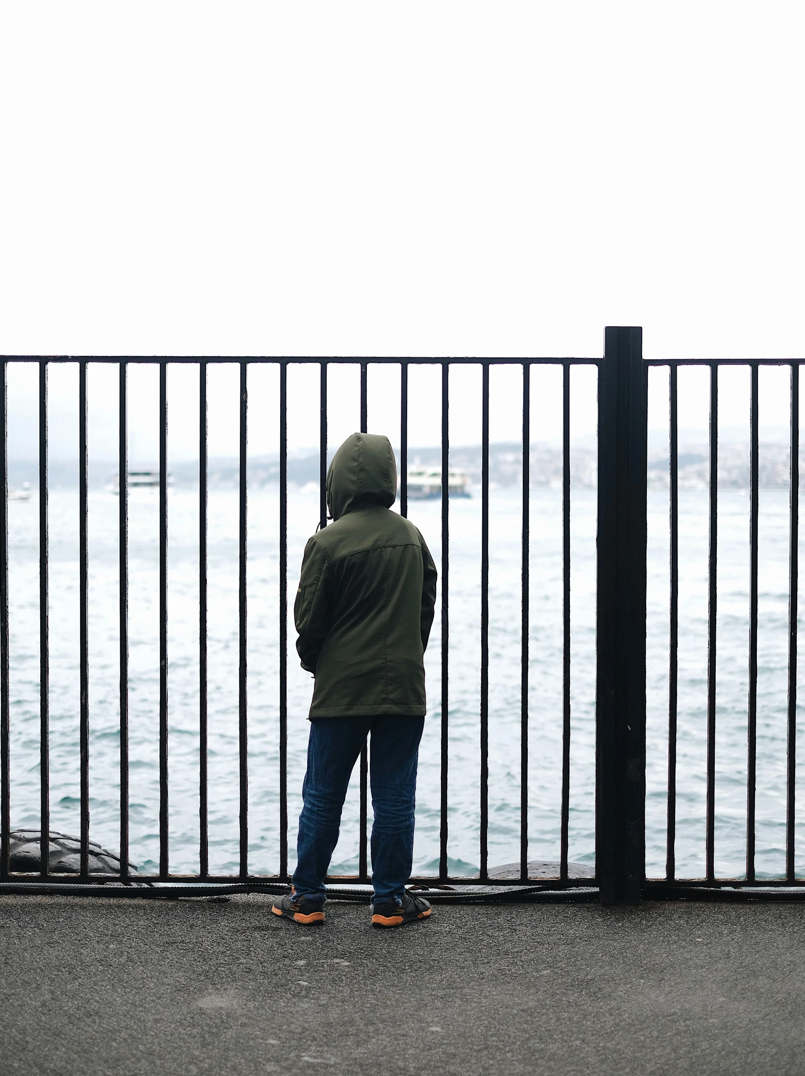 man standing by the side of a fence looking at the water